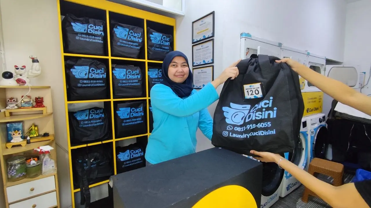 Staff menyerahkan cucian yang sudah selesai ke pelanggan
